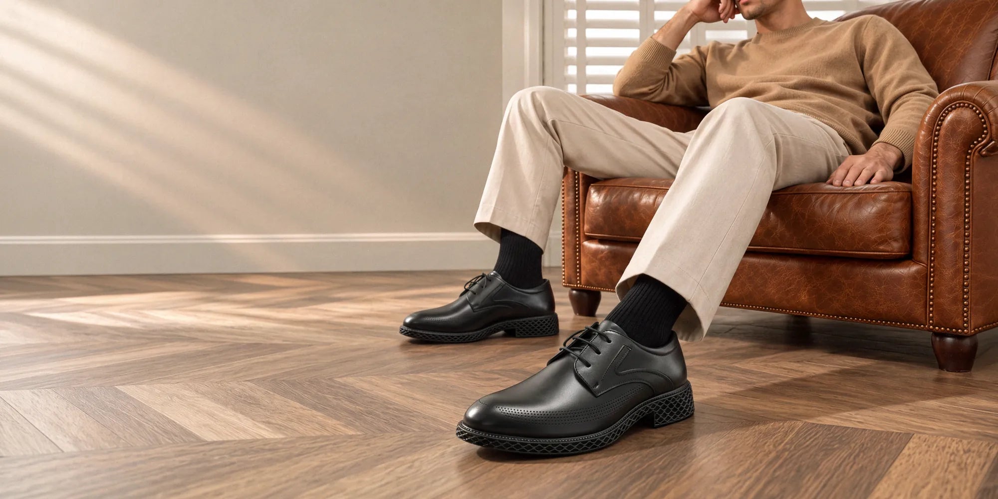 Man seated in a leather armchair wearing black Gravitas Grid Derby shoes